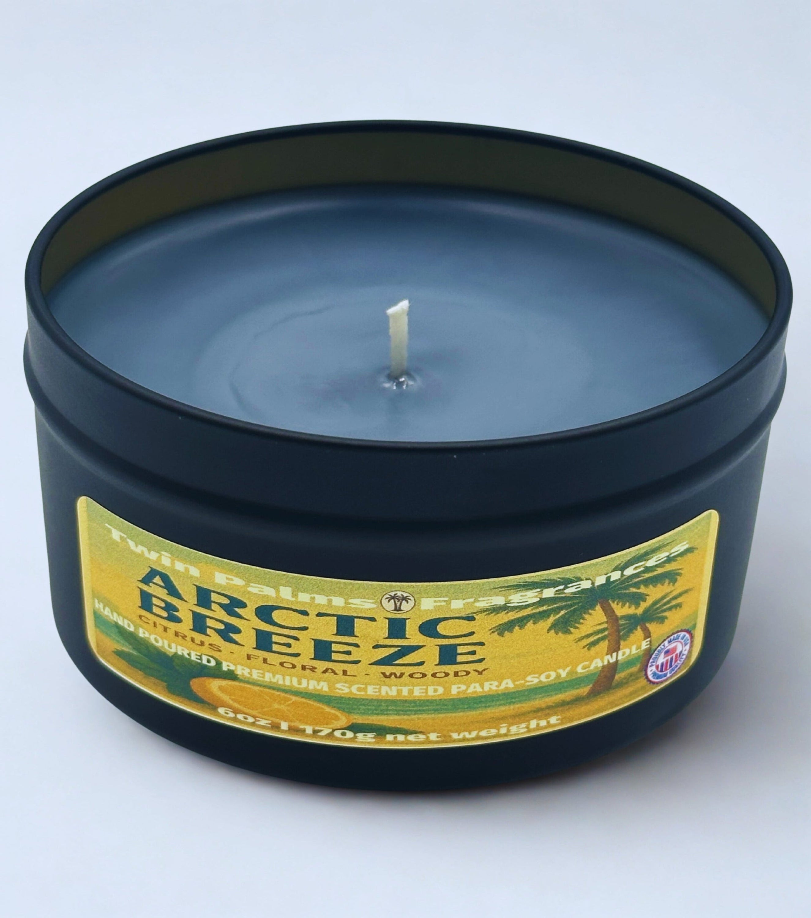 Candle in a tin labeled 'Arctic Breeze' by Twin Palms Fragrances on a white background