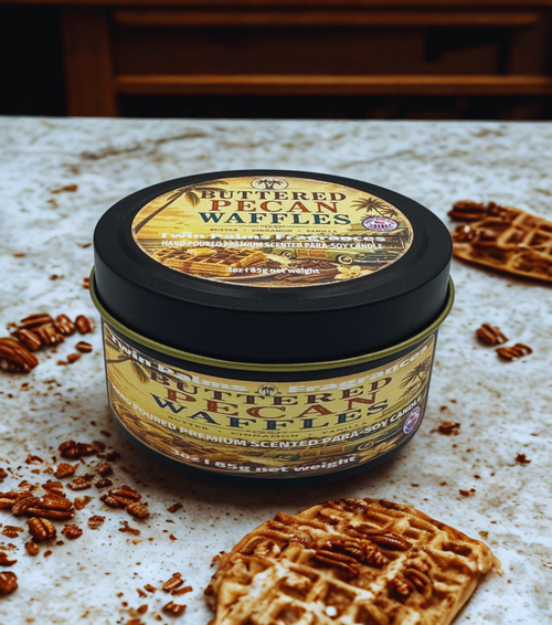 Tin of 'Buttered Pecan Waffles' candles on a textured surface with waffle cookies.