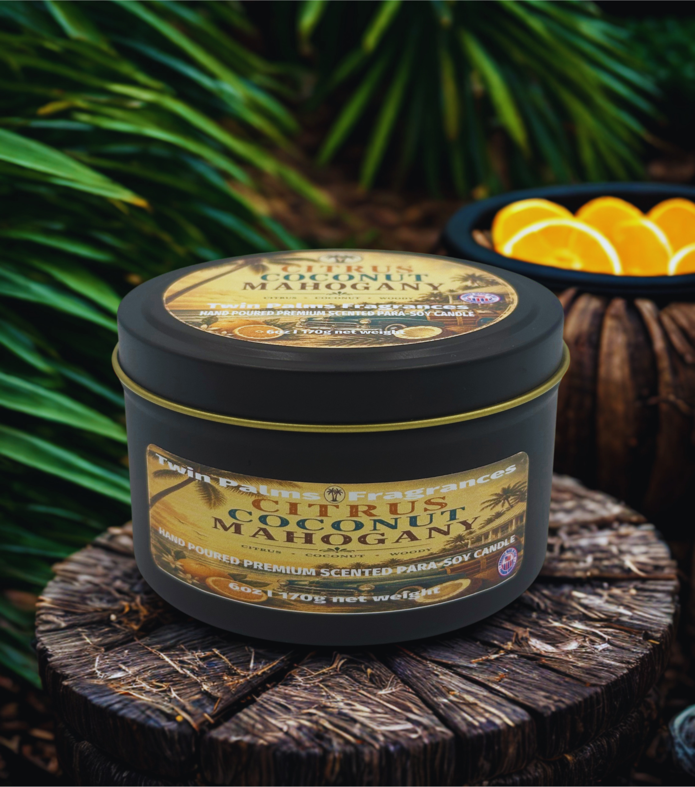Tin of 'Citrus Coconut Mahogany' candle on a wooden surface with greenery in the background