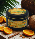 Candle jar labeled 'Citrus Coconut Sunshine' with oranges and coconuts on a wooden surface