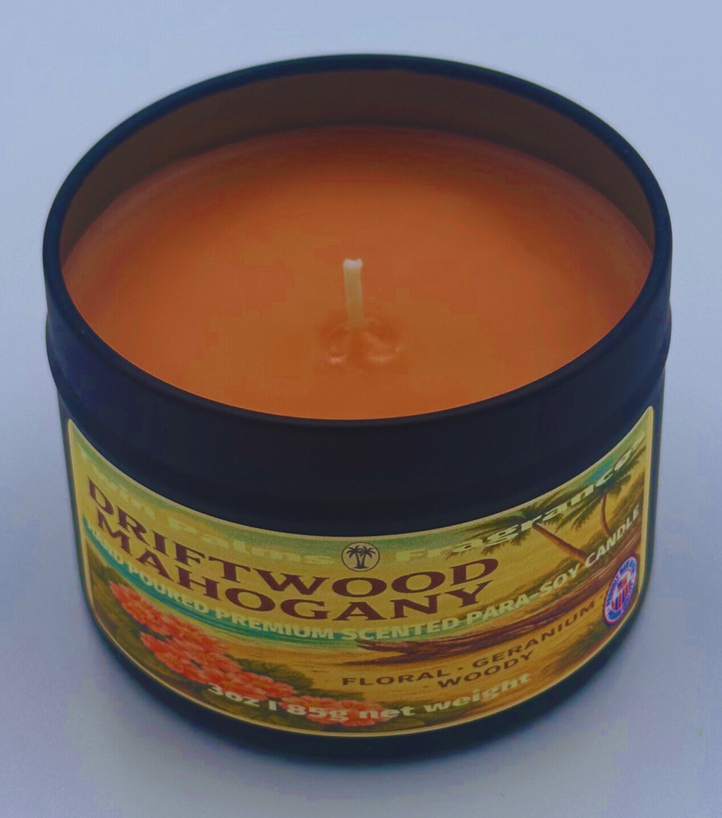 Candle in a tin labeled 'Driftwood Mahogany' on a light blue background