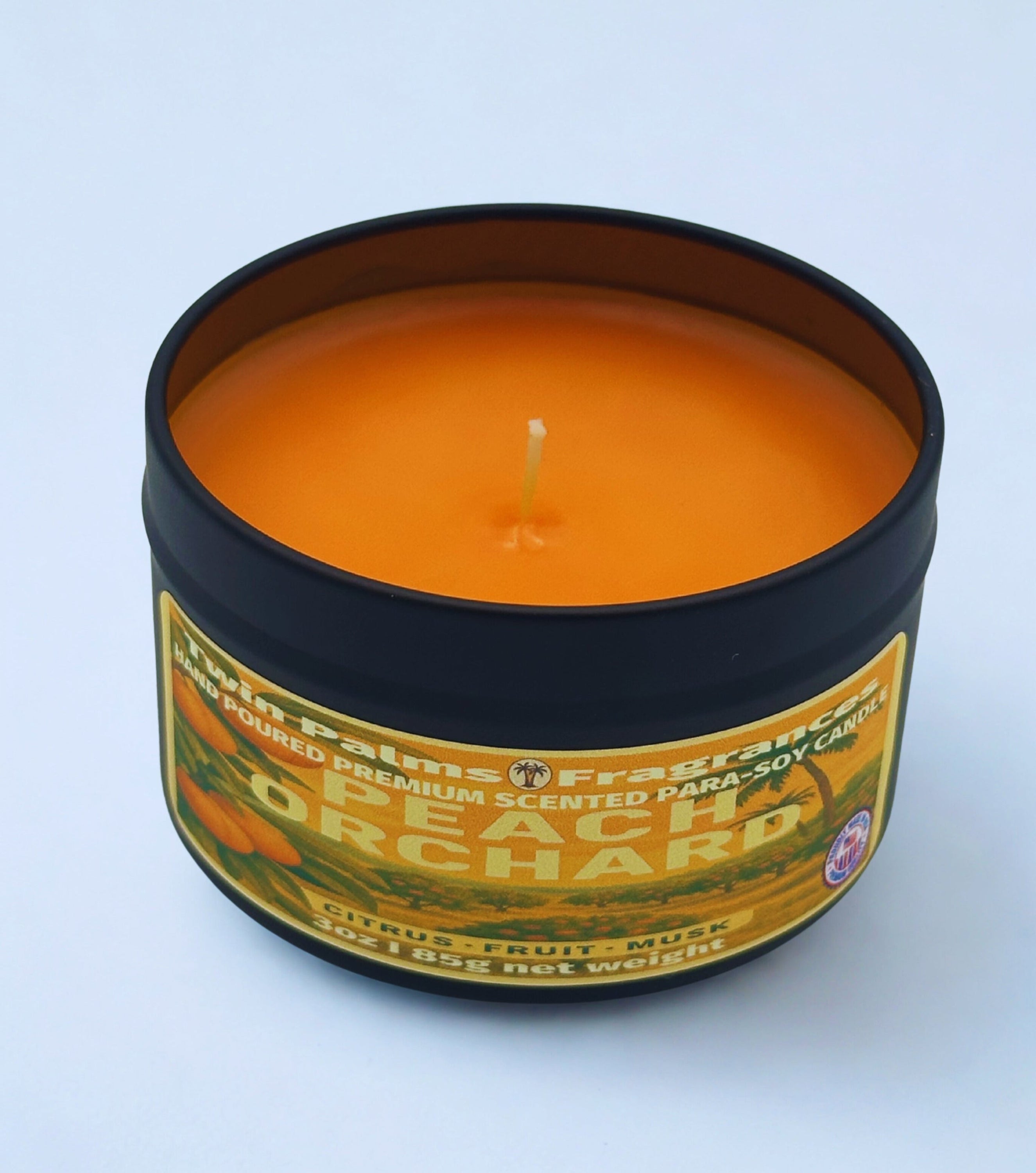 Candle in a tin labeled 'Peach Orchard' on a light blue background