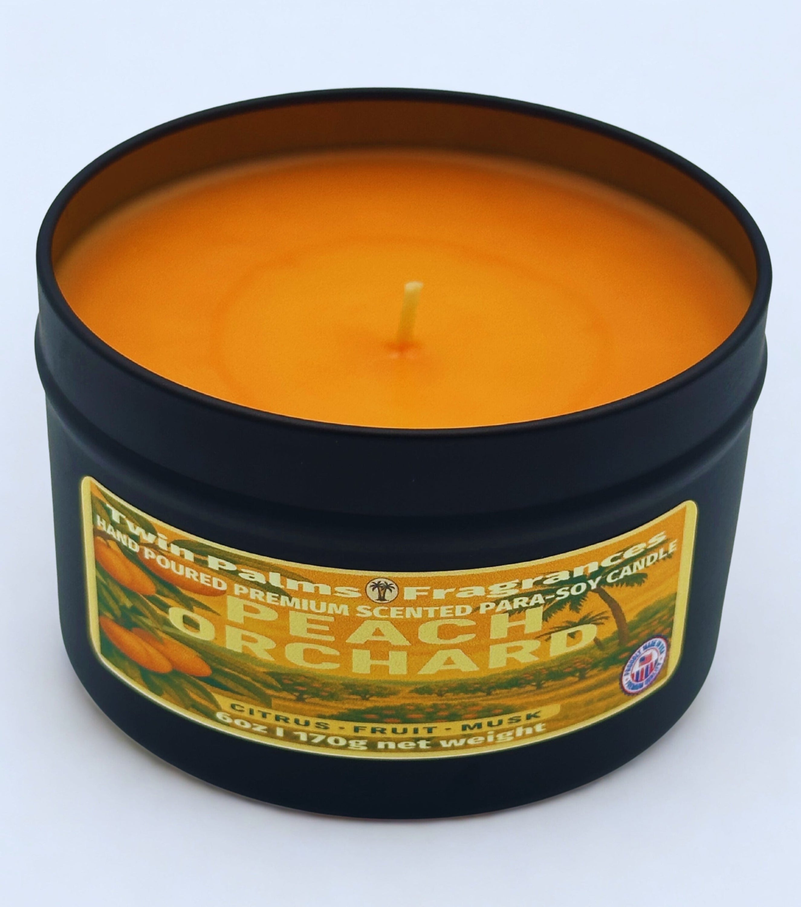Candle in a tin labeled 'Peach Orchard' by Twin Palms Fragrances on a white background