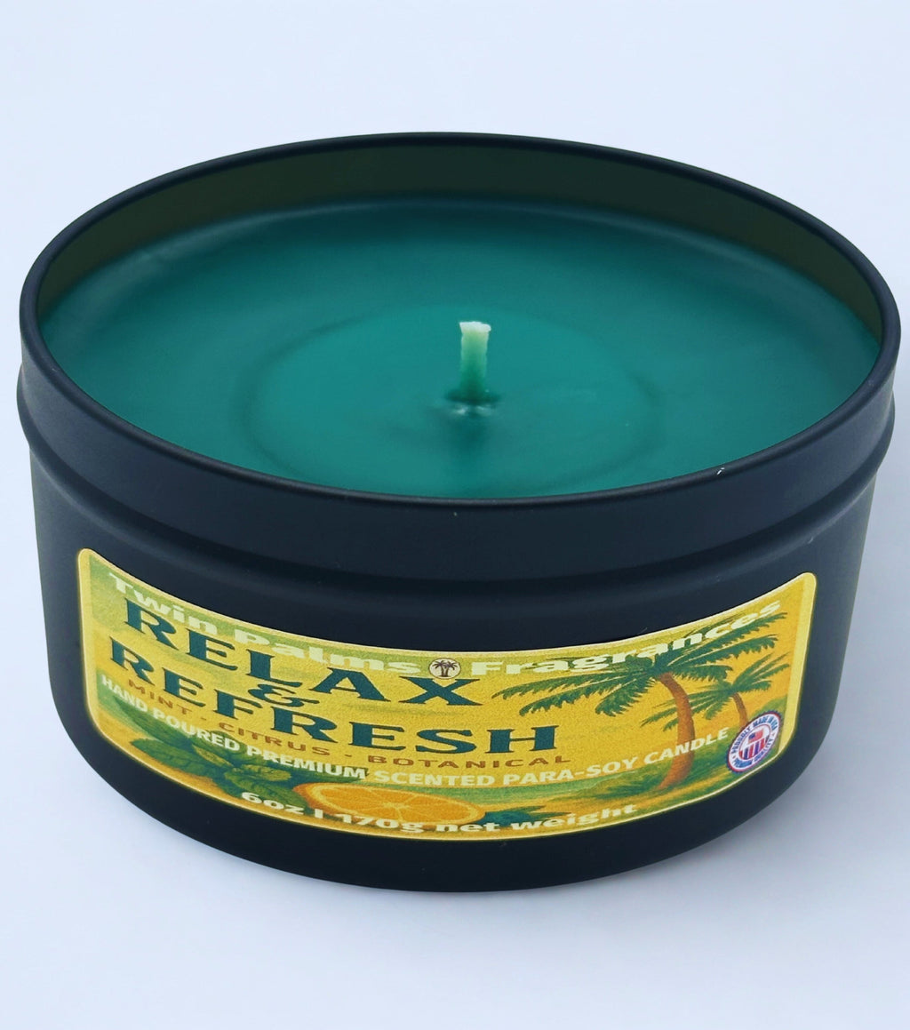 Twin Palms Fragrances candle in a black tin with a label reading 'Relax and Refresh' on a white background