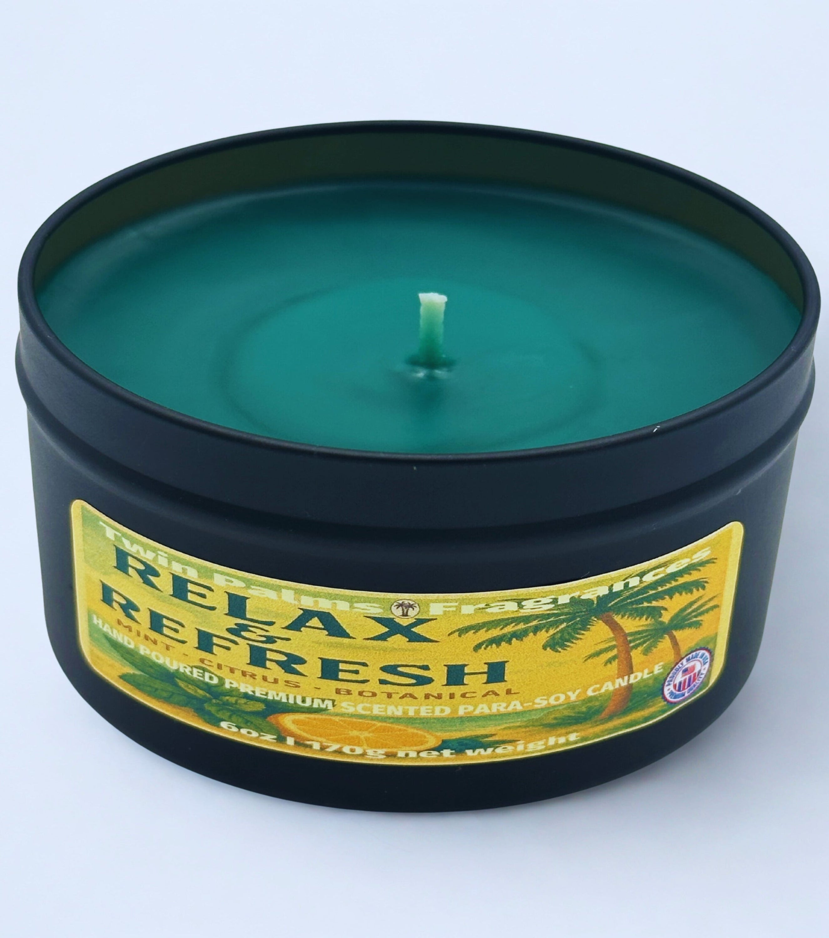 Twin Palms Fragrances candle in a black tin with a label reading 'Relax and Refresh' on a white background