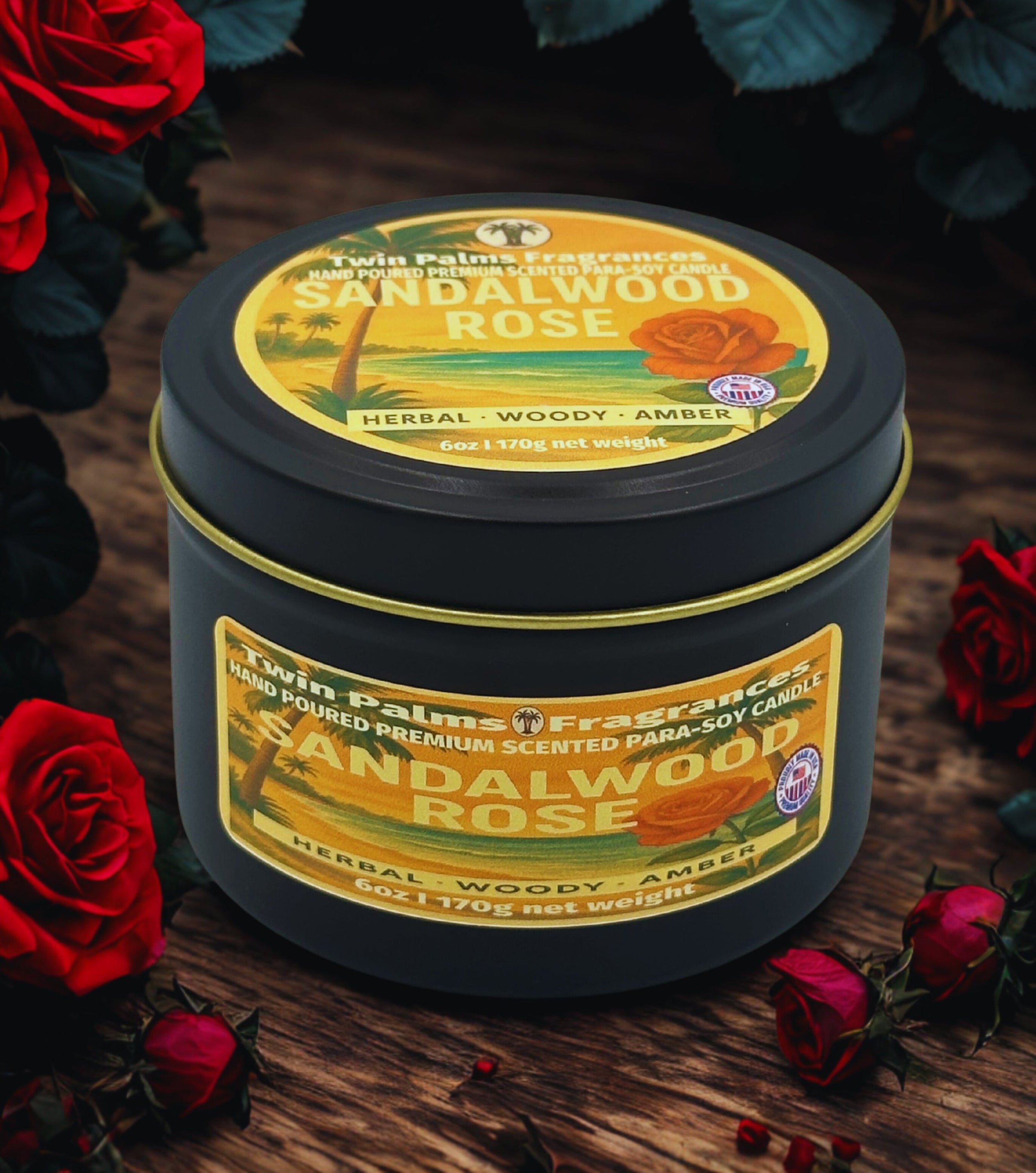 Twin Palms Fragrances Sandalwood Rose candle in a black tin with a yellow label on a wooden surface surrounded by red roses.