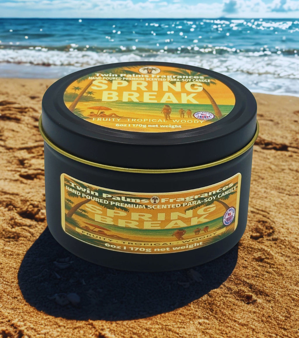 Twin Palms Fragrances candle tin labeled 'Spring Break' on a sandy beach with ocean in the background