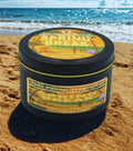 Twin Palms Fragrances candle tin labeled 'Spring Break' on a sandy beach with ocean in the background
