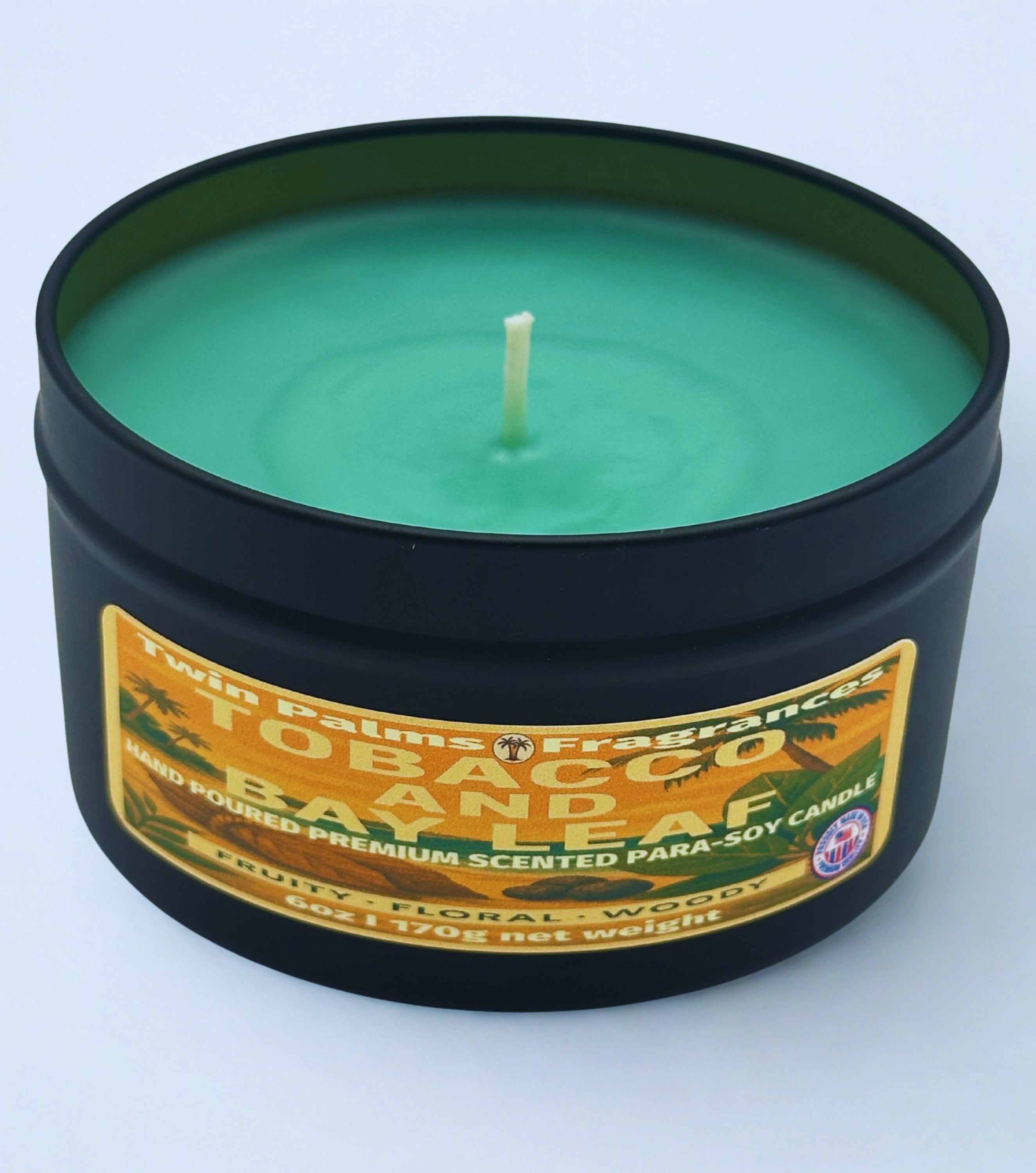 Twin Palms Fragrances Tobacco and Bay Leaf candle in a tin container with a label on a light blue background