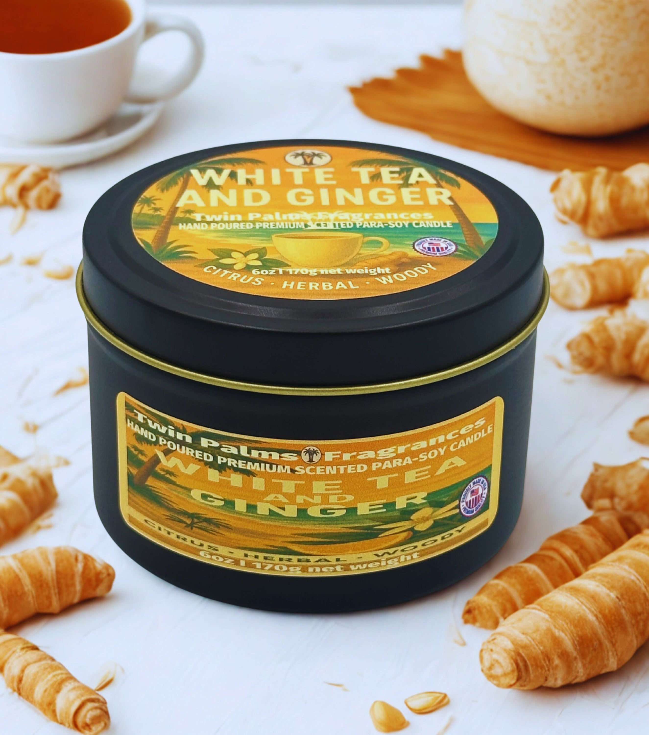 Twin Palms Fragrances White Tea and Ginger candle in a tin surrounded by croissants on a white surface